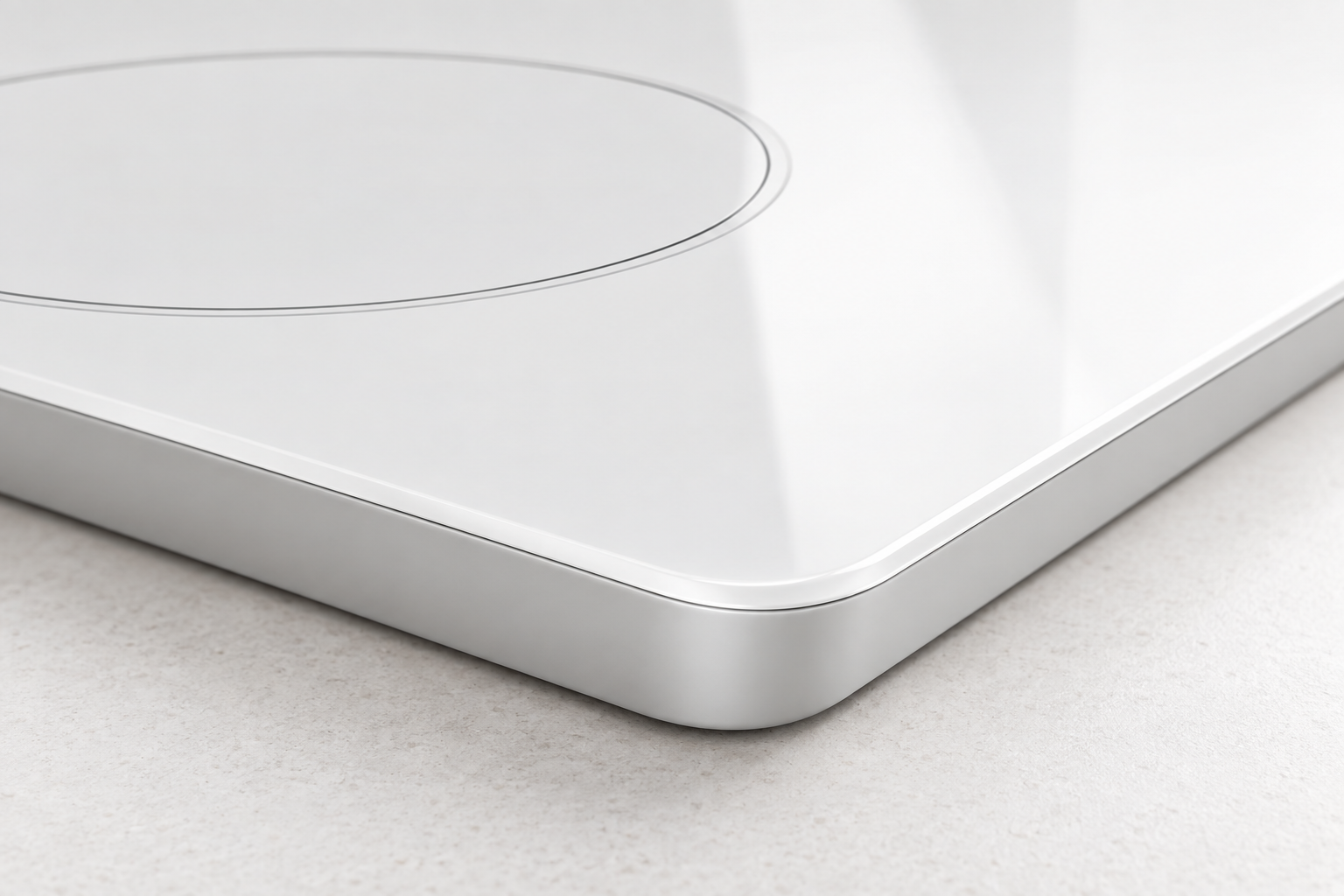 Close view of a pristine rounded edge on an opaque white glass-ceramic cooktop panel